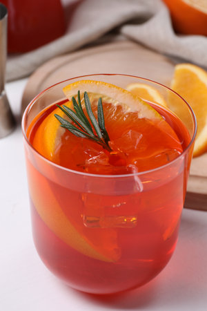 Aperol spritz cocktail, ice cubes, rosemary and orange slices in glass on white wooden table, closeupの写真素材