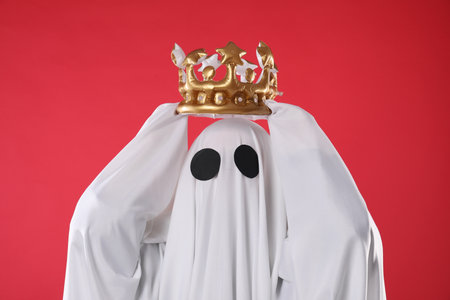 Person in ghost costume wearing luxurious crown on red backgroundの写真素材