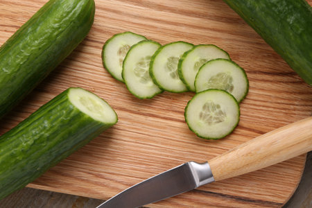 Cut cucumber and knife on wooden board, top viewの写真素材