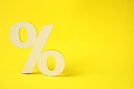 Wooden percent sign on yellow background. Space for textの写真素材