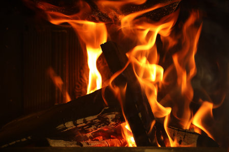 Bonfire with burning firewood on dark background, closeup