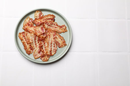 Delicious fried bacon slices on white wooden table, top view. Space for textの写真素材