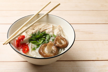 Delicious ramen with meat in bowl and chopsticks on wooden table. Space for textの写真素材