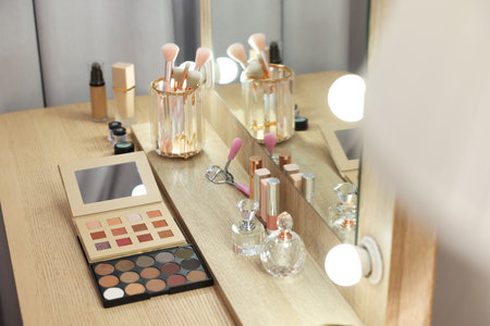 Different beauty products and perfumes on wooden dressing table in roomの写真素材