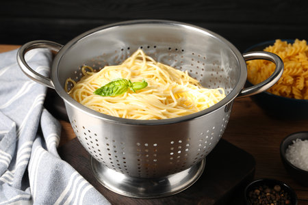 Cooked pasta in metal colander and spices on table, closeupの写真素材