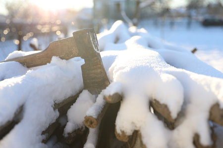 Metal ax on snowy firewood outdoors on sunny winter dayの写真素材