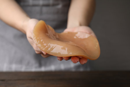 Making kombucha. Woman holding Scoby fungus at wooden table, closeup