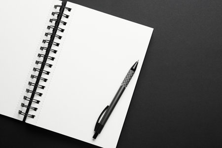 Notebook and pen on black background, top view. Space for textの写真素材