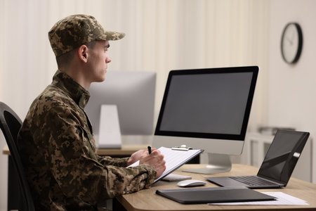 Military service. Soldier with clipboard working at table in officeの写真素材