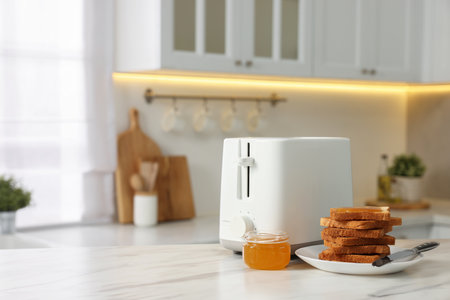 Breakfast served in kitchen. Toaster, crunchy bread and honey on white marble table. Space for text