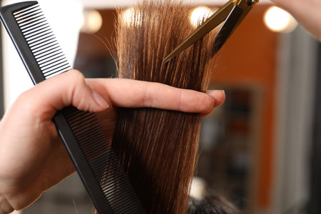 Hairdresser cutting client's hair with scissors in salon, closeupの写真素材