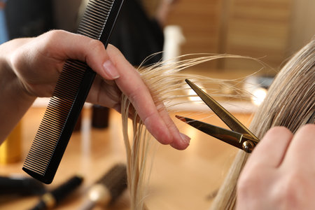 Hairdresser cutting client's hair with scissors in salon, closeupの写真素材