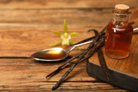 Aromatic vanilla extract, pods and flower on wooden table. Space for textの写真素材
