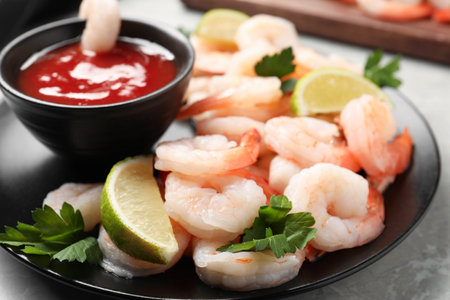 Tasty boiled shrimps with sauce cocktail, parsley and lime on light gray table, closeupの写真素材