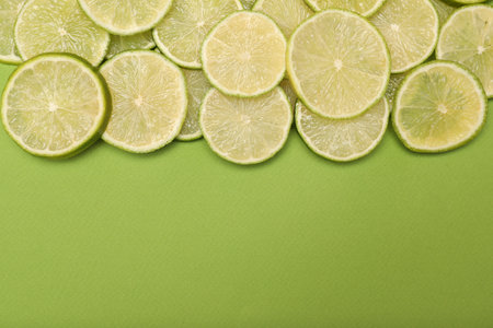 Many juicy lime slices on green background, flat lay. Space for textの写真素材