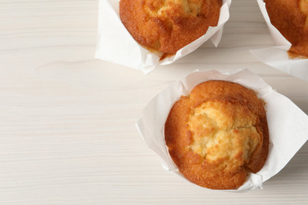 Tasty muffins on white wooden table, flat lay. Space for text