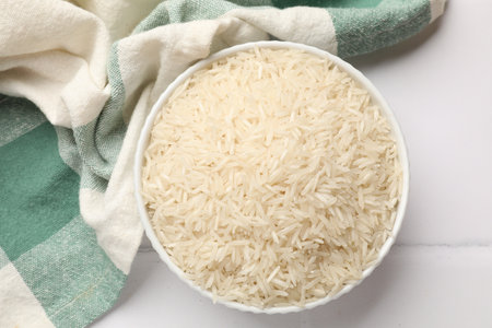 Raw basmati rice in bowl on white tiled table, top viewの写真素材