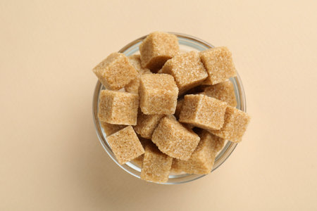 Brown sugar cubes in bowl on beige background, top viewの写真素材