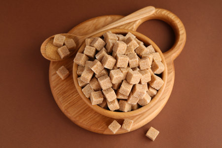 Brown sugar cubes in bowl and spoon on color background, top viewの写真素材