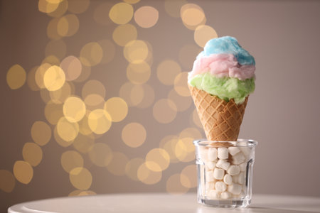 Sweet cotton candy in waffle cone on table against blurred lights, closeup. Space for textの写真素材