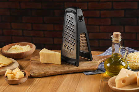 Different types of cheese and grater on wooden tableの写真素材