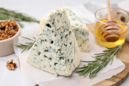 Tasty blue cheese with rosemary, honey and walnuts on white table, closeupの写真素材
