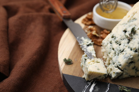 Tasty blue cheese with thyme and knife on wooden board, closeup. Space for textの写真素材