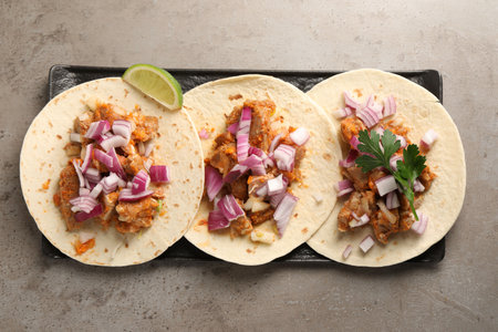 Delicious tacos with vegetables, meat and lime on gray textured table, top viewの写真素材