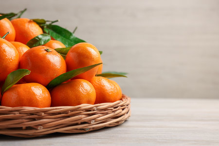 Fresh ripe juicy tangerines and green leaves on white wooden table, closeup with space for textの写真素材