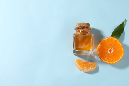Aromatic tangerine essential oil in bottle and citrus fruit on light blue table, top view. Space for textの写真素材