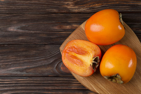 Whole and cut delicious ripe persimmons on wooden table, top view. Space for textの写真素材