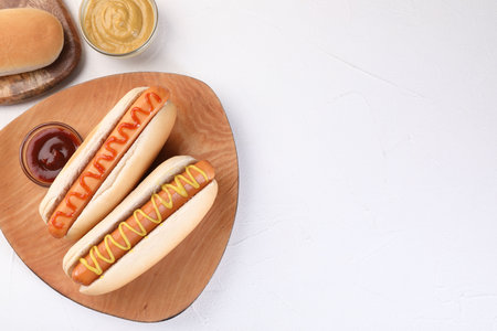 Tasty hot dogs with ketchup and mustard on white table, flat lay. Space for textの写真素材