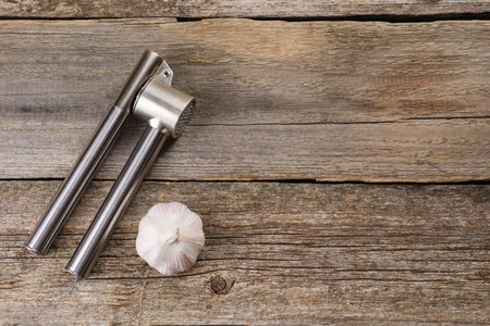 Garlic press and bulb on wooden table, top view. Space for textの写真素材