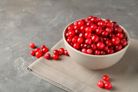 Cranberries in bowl on light gray table, closeup. Space for textの写真素材