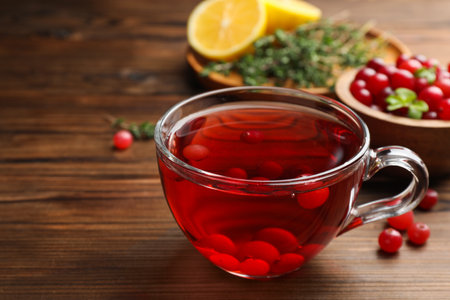 Tasty hot cranberry tea in glass cup and fresh berries on wooden tableの写真素材