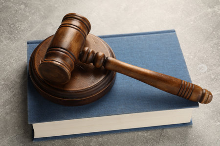 Wooden gavel, sound block and book on gray textured table, closeup