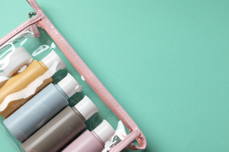 Cosmetic travel kit in plastic bag on turquoise background, top view. Space for textの写真素材