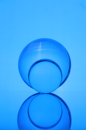 Transparent glass balls on mirror surface against blue backgroundの写真素材