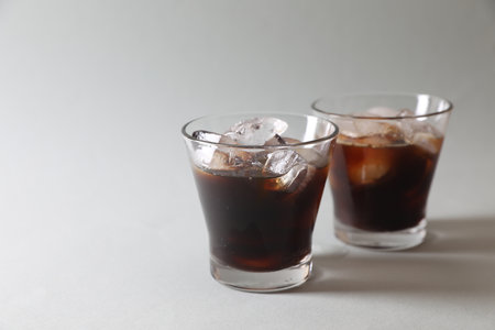Refreshing iced coffee in glasses on gray background. Space for text