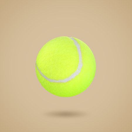 One tennis ball in air on beige backgroundの写真素材
