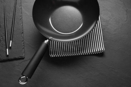 Empty iron wok and chopsticks on black table, flat layの写真素材