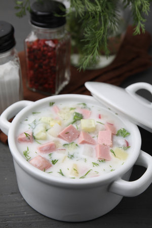 Delicious cold summer soup (okroshka) with boiled sausage in pot on gray wooden tableの写真素材