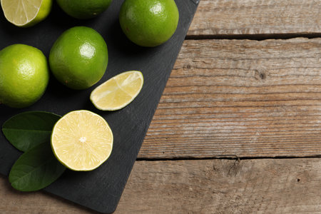 Fresh limes and green leaves on wooden table, top view. Space for textの写真素材