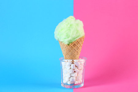 Sweet cotton candy in waffle cone on color backgroundの写真素材