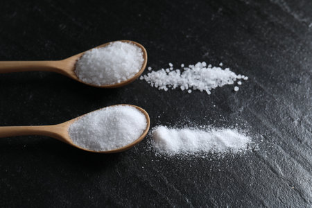 Organic salt in spoons on black table, closeupの写真素材