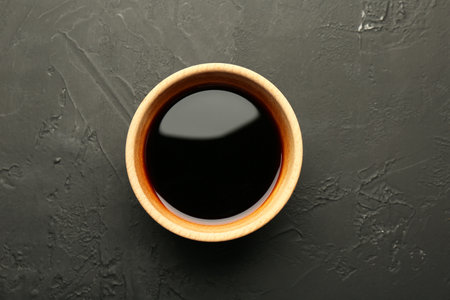 Soy sauce in wooden bowl on black textured table, top viewの写真素材