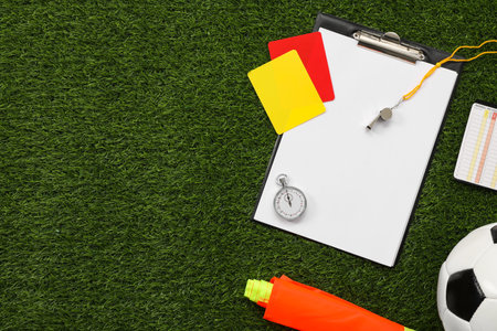 Soccer ball and different referee equipment on green grass, flat lay. Space for textの写真素材