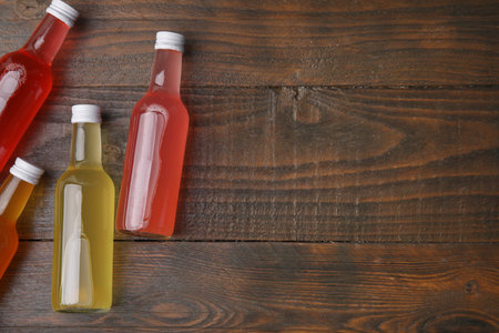 Delicious kombucha in glass bottles on wooden table, flat lay. Space for textの写真素材