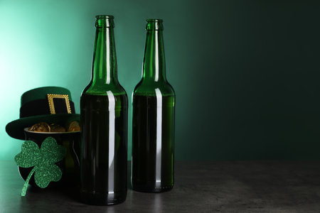 St. Patrick's day celebration. Beer in green bottles, leprechaun hat, pot of gold and decorative clover leaf on gray table. Space for textの写真素材