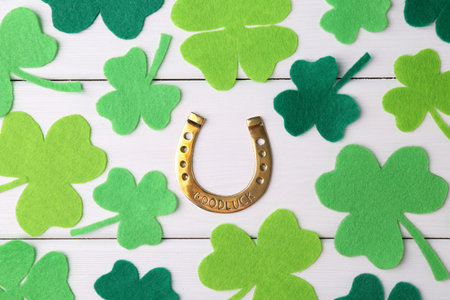 St. Patrick's day. Golden horseshoe and green decorative clover leaves on white wooden table, flat layの写真素材